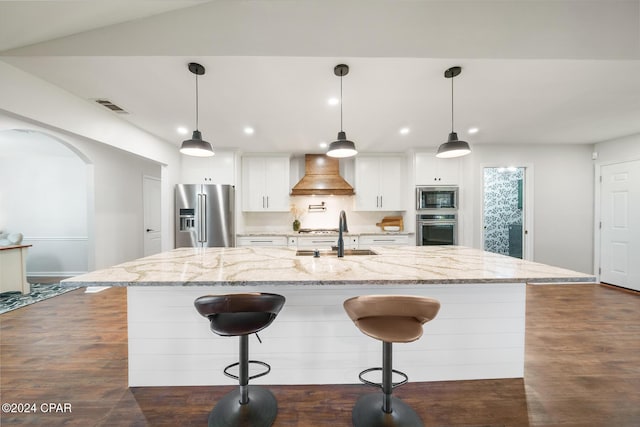 kitchen with light stone countertops, appliances with stainless steel finishes, a spacious island, white cabinets, and custom exhaust hood