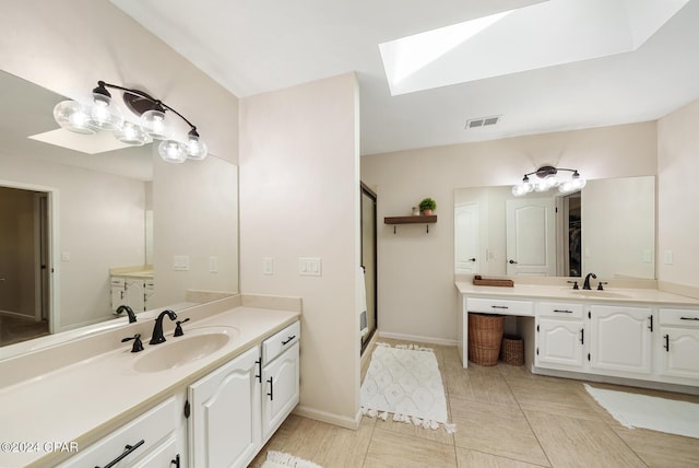 bathroom featuring vanity, a skylight, tile patterned floors, and an enclosed shower