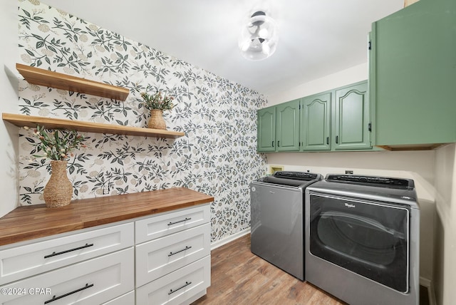 laundry area featuring separate washer and dryer, cabinets, and light wood-type flooring