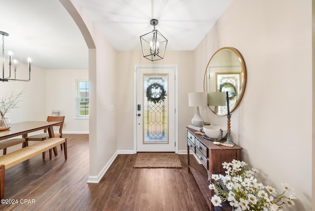 entrance foyer with a wealth of natural light, dark wood-type flooring, and an inviting chandelier