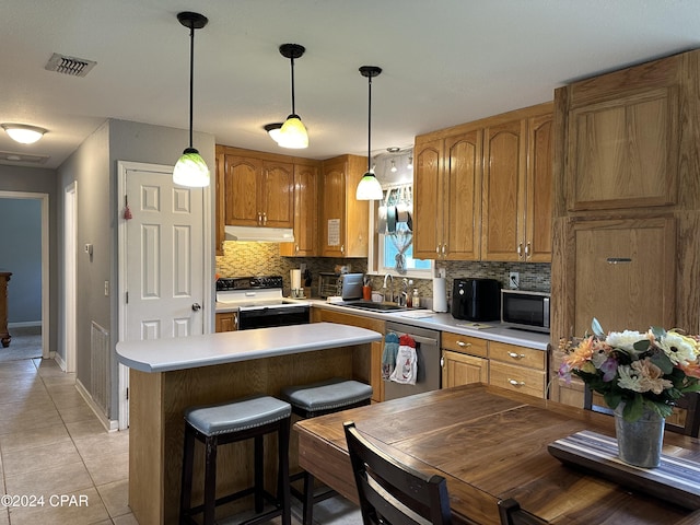 kitchen featuring tasteful backsplash, stainless steel appliances, sink, pendant lighting, and light tile patterned flooring