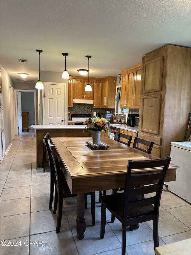 tiled dining area with sink and a textured ceiling