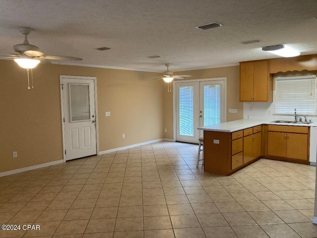 kitchen with french doors, sink, kitchen peninsula, a textured ceiling, and light tile patterned flooring