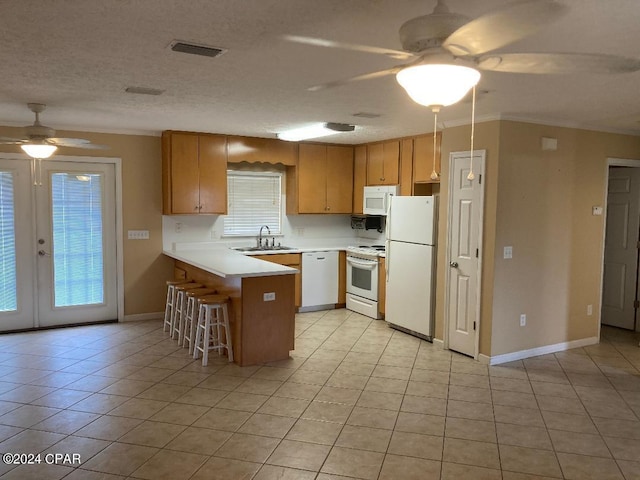 kitchen with white appliances, french doors, sink, light tile patterned floors, and kitchen peninsula