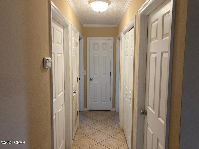 corridor with a textured ceiling, ornamental molding, and light tile patterned flooring