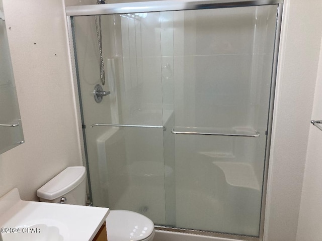 bathroom with vanity, toilet, and a shower with shower door