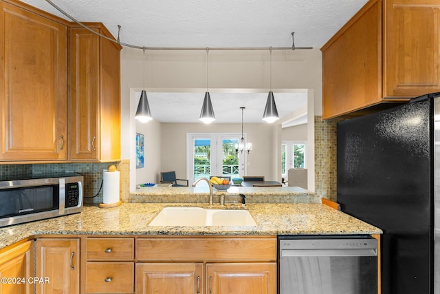 kitchen with sink, light stone counters, kitchen peninsula, decorative backsplash, and appliances with stainless steel finishes