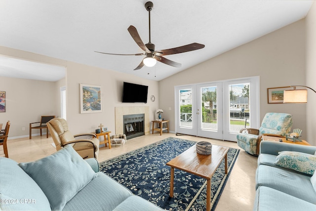 living room featuring a tiled fireplace, ceiling fan, and vaulted ceiling