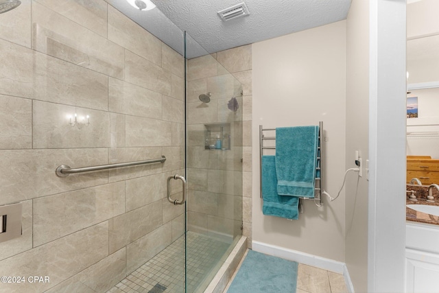 bathroom featuring tile patterned floors, vanity, a textured ceiling, and walk in shower