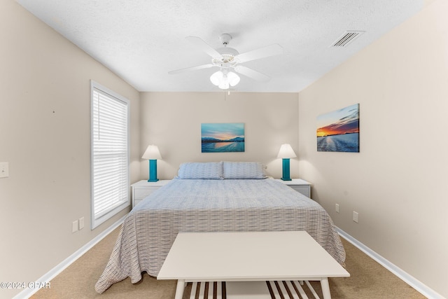 carpeted bedroom with ceiling fan and a textured ceiling