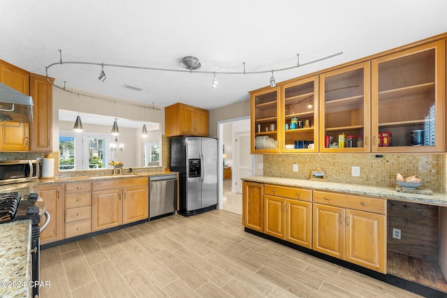 kitchen with backsplash, light stone counters, pendant lighting, and appliances with stainless steel finishes