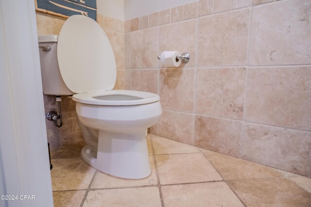 bathroom featuring toilet and tile walls