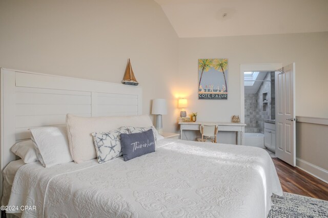 bedroom featuring dark hardwood / wood-style flooring, ensuite bathroom, and lofted ceiling with skylight