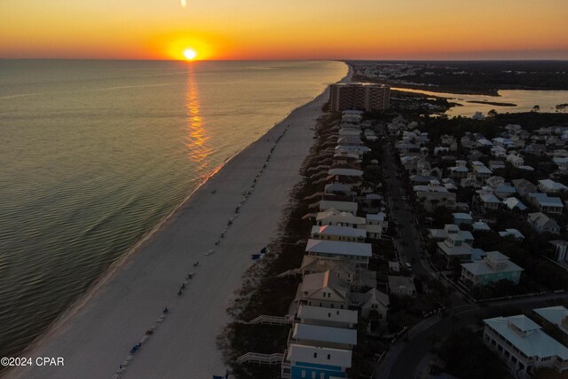 aerial view at dusk featuring a water view and a view of the beach