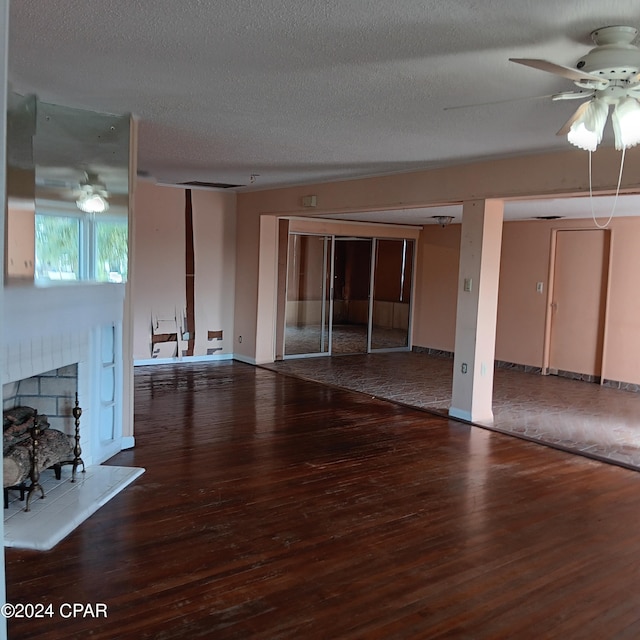 unfurnished living room featuring wood-type flooring, a textured ceiling, and a brick fireplace