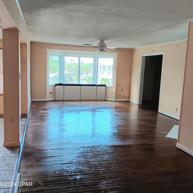 spare room featuring a textured ceiling, ceiling fan, ornamental molding, and dark wood-type flooring