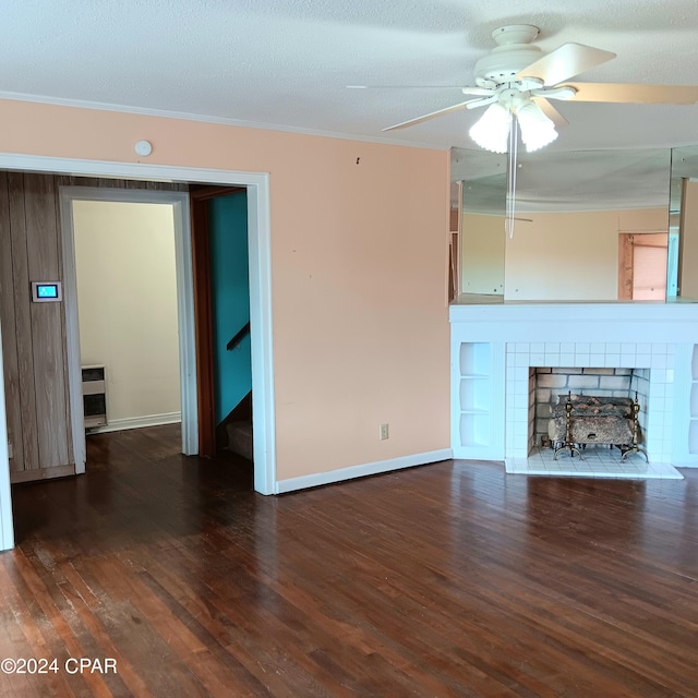 unfurnished living room featuring dark hardwood / wood-style floors, ceiling fan, a textured ceiling, and a tiled fireplace