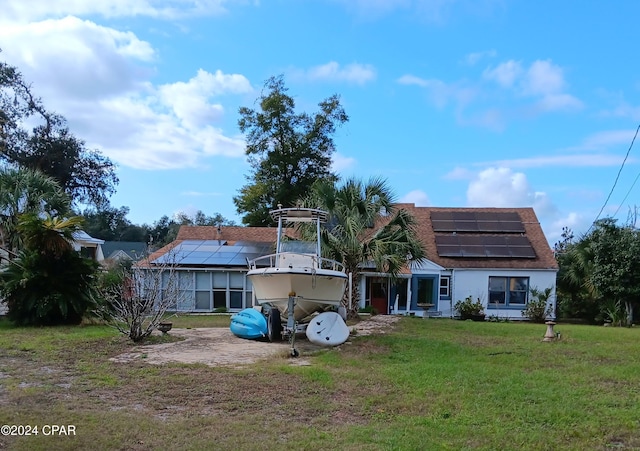 rear view of house featuring a yard and solar panels