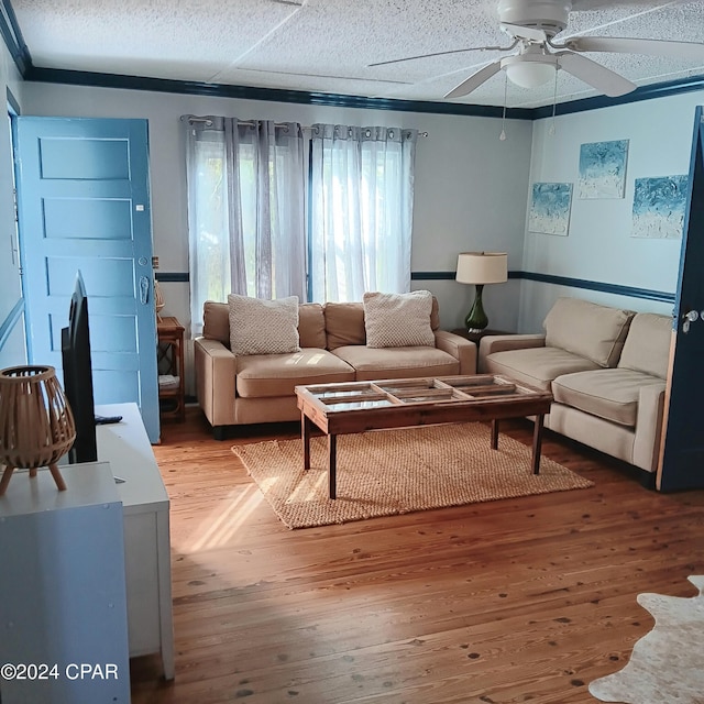 living room featuring hardwood / wood-style floors, ceiling fan, and a textured ceiling