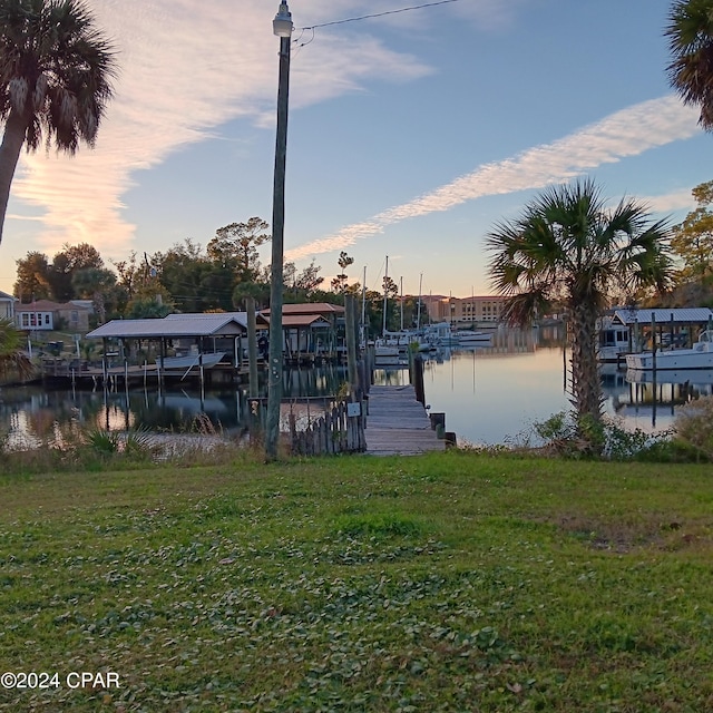 view of dock featuring a water view and a yard