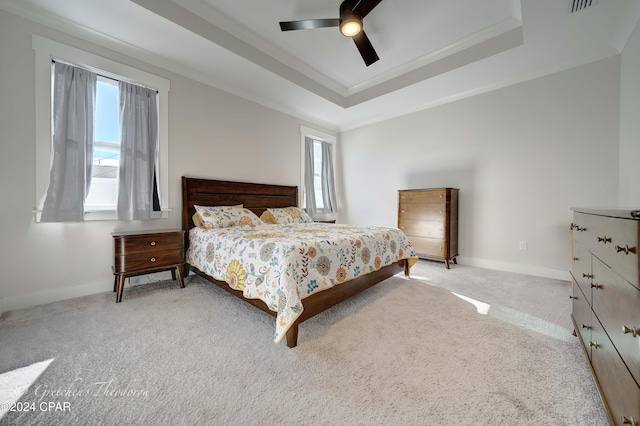 carpeted bedroom featuring a raised ceiling, ceiling fan, and crown molding