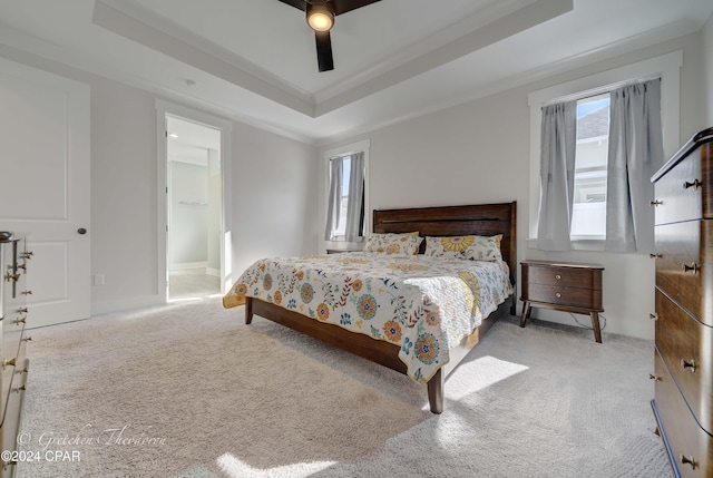 bedroom featuring light carpet, a raised ceiling, ceiling fan, and crown molding