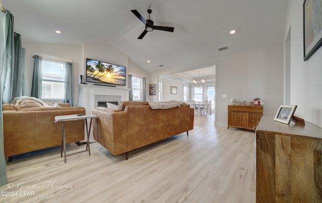 living room with a wealth of natural light, ceiling fan with notable chandelier, lofted ceiling, and light wood-type flooring