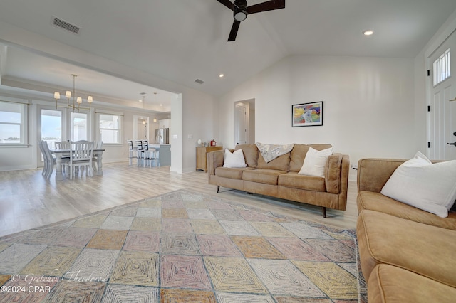 living room featuring lofted ceiling, light hardwood / wood-style floors, and ceiling fan with notable chandelier