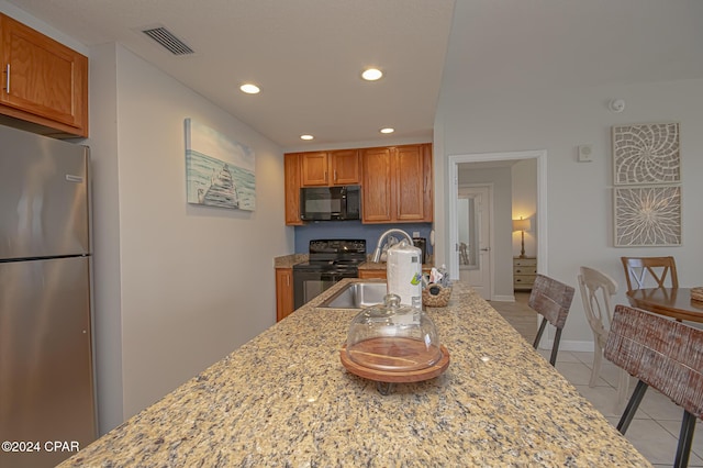 kitchen with black appliances, light stone countertops, sink, and light tile patterned floors