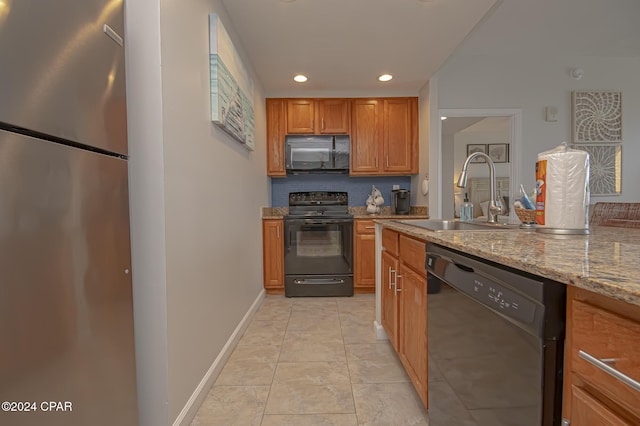 kitchen with black appliances, light stone counters, light tile patterned floors, and sink