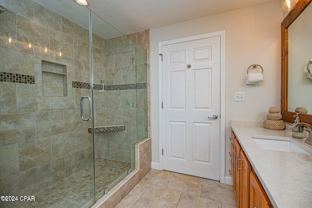 bathroom featuring a textured ceiling, vanity, and walk in shower