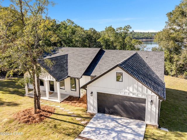 modern farmhouse with a water view, a garage, and a front lawn