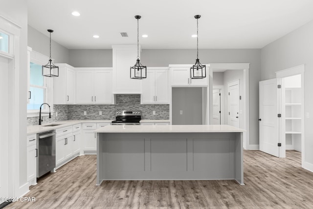 kitchen with white cabinetry, a kitchen island, light wood-type flooring, and appliances with stainless steel finishes