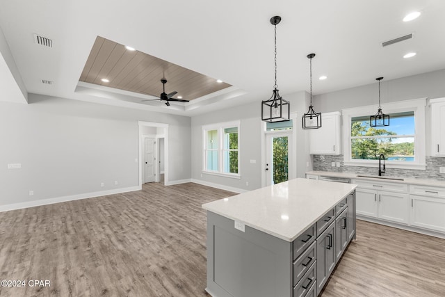 kitchen featuring white cabinets, ceiling fan, a raised ceiling, and sink