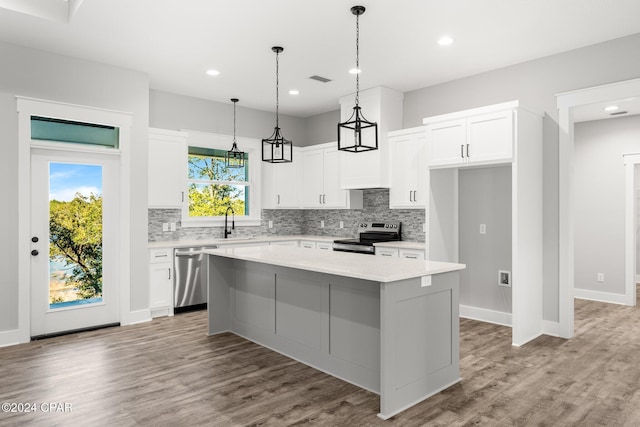 kitchen featuring white cabinetry, a center island, stainless steel appliances, light hardwood / wood-style flooring, and decorative backsplash