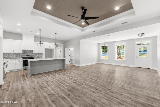 living room featuring a healthy amount of sunlight, a tray ceiling, ceiling fan, and light hardwood / wood-style floors