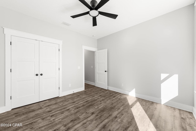 unfurnished bedroom with ceiling fan, a closet, and dark hardwood / wood-style floors