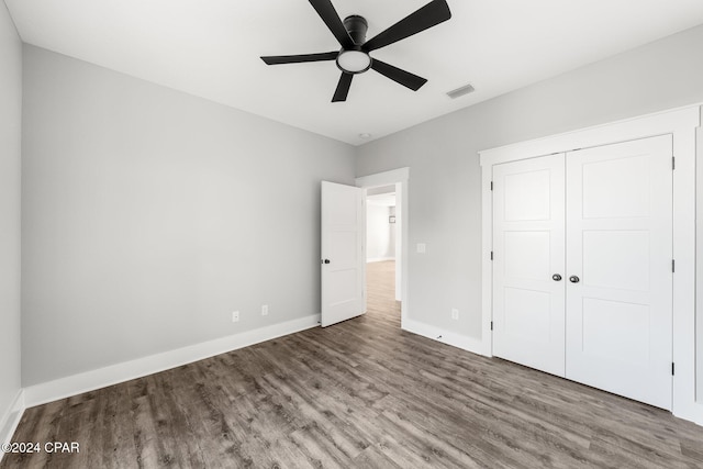 unfurnished bedroom with ceiling fan, wood-type flooring, and a closet