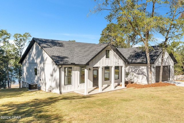 rear view of house featuring cooling unit, a garage, a yard, and a patio