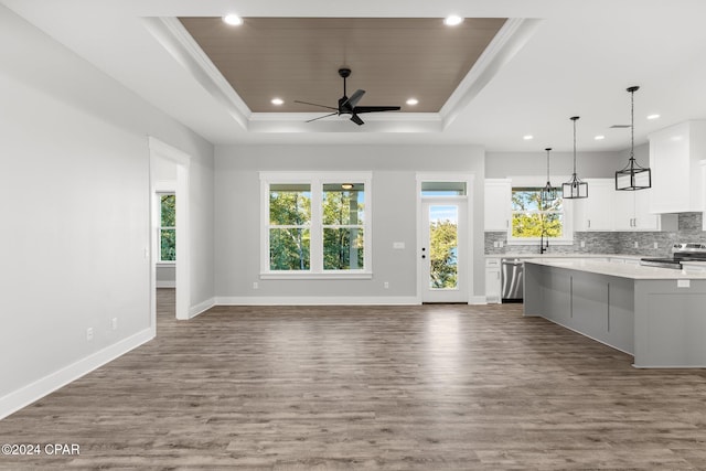 unfurnished living room with dark hardwood / wood-style floors, a healthy amount of sunlight, and a tray ceiling