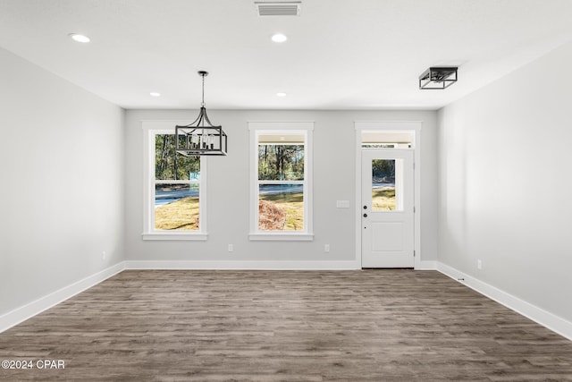 unfurnished dining area featuring dark hardwood / wood-style flooring and an inviting chandelier