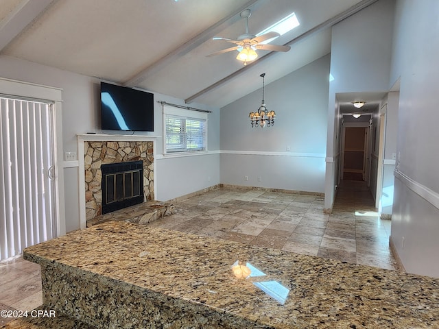 living room with beam ceiling, ceiling fan with notable chandelier, high vaulted ceiling, and a stone fireplace