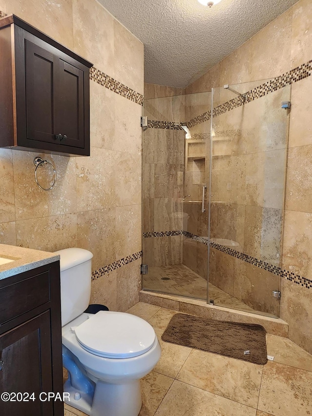 bathroom featuring vanity, an enclosed shower, a textured ceiling, and tile walls