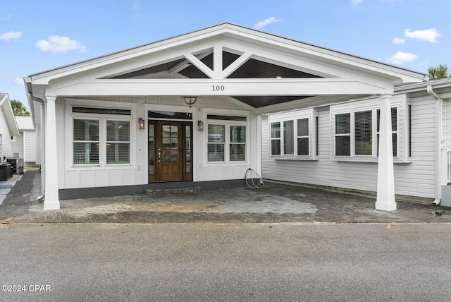 view of front of home featuring board and batten siding, cooling unit, and a carport