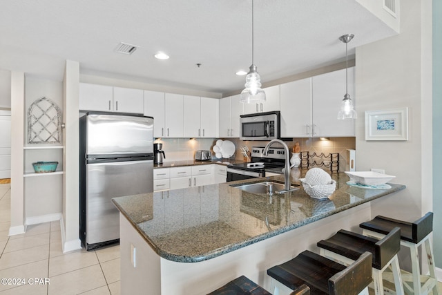 kitchen with pendant lighting, decorative backsplash, white cabinetry, and stainless steel appliances