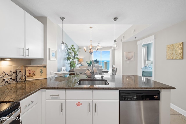 kitchen with dark stone counters, sink, white cabinets, and stainless steel dishwasher