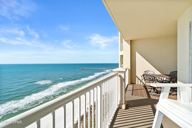 balcony featuring a view of the beach and a water view