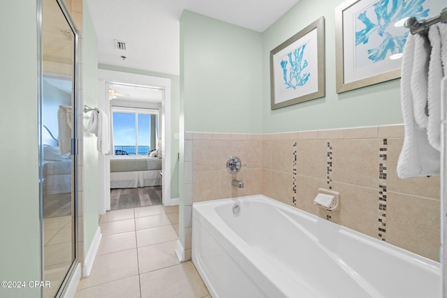 bathroom with ceiling fan, tile patterned flooring, plus walk in shower, and tile walls