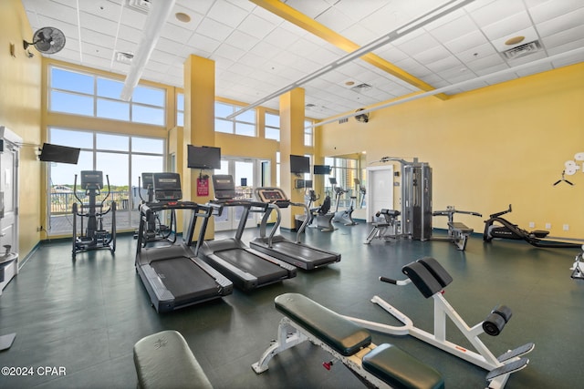 gym with a paneled ceiling, a wealth of natural light, and a high ceiling