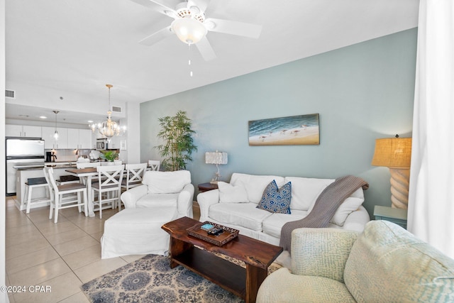 tiled living room with ceiling fan with notable chandelier